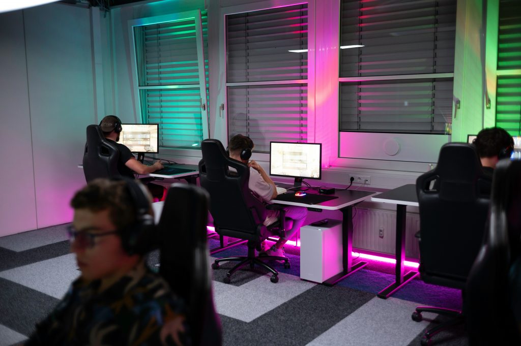 Students sitting at a desk with a gaming setup with vibrant RGB lighting.